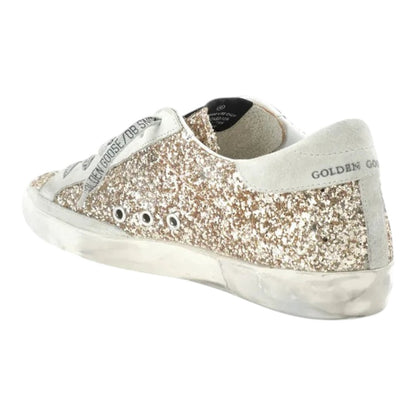 Luxurykicks.store Golden Goose Superstar low top sneakers in gold glitter with distressed rubber sole and logo laces.
