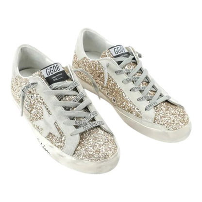 Luxurykicks.store Golden Goose Superstar low top sneakers in gold glitter with grey logo laces and distressed soles.