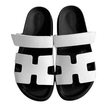 Luxurykicks.store Hermes Chypre sandals in white leather with a black footbed and adjustable velcro strap