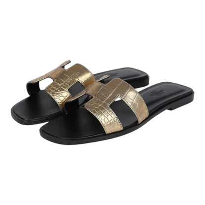 Luxurykicks.store Hermès Oran sandals in metallic gold crocodile-embossed leather with signature H-strap design.